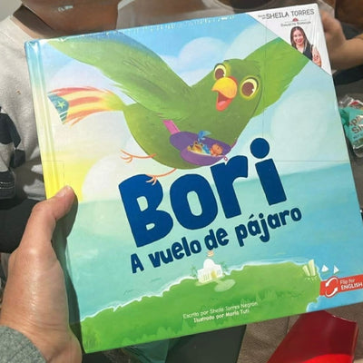 Fotografía compartida por un cliente sosteniendo en sus manos el libro "Bori: A Vuelo de Pájaro", mostrando el tamaño real del producto y los colores vibrantes de su portada.