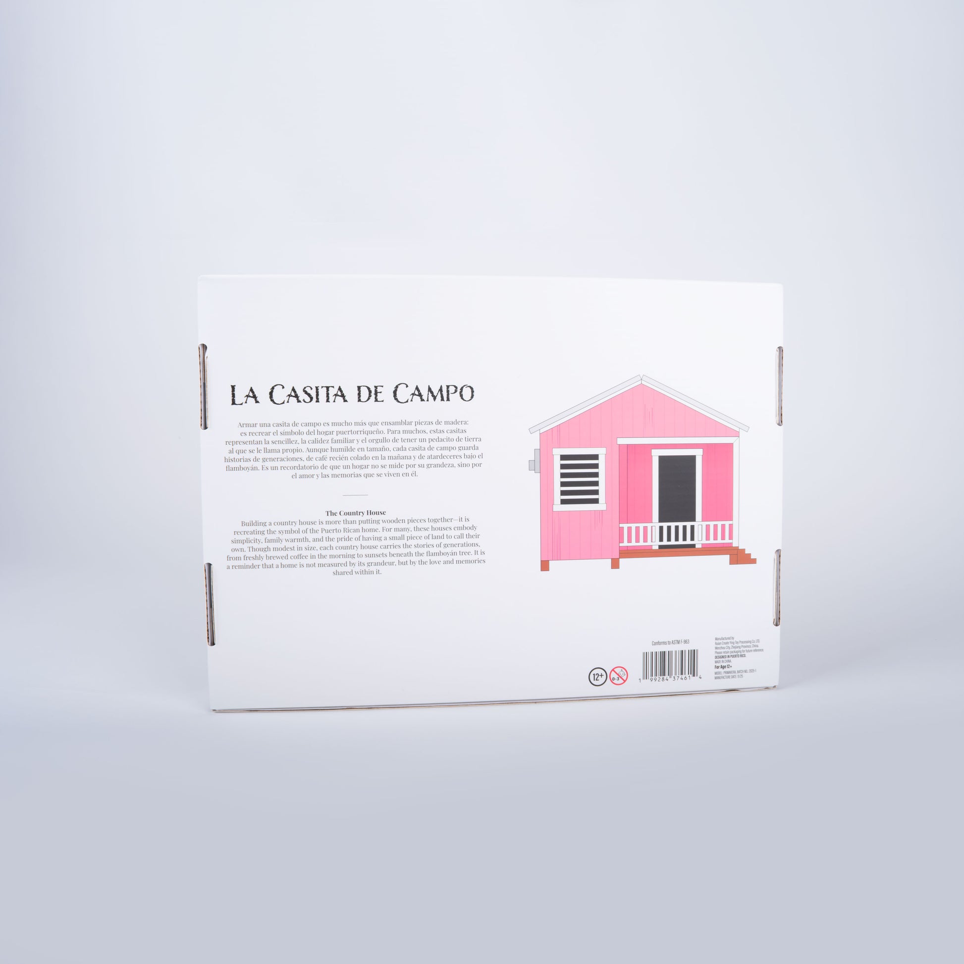 Fotografía de estudio de la parte trasera de la caja de La Casita de Campo, con la reseña bilingüe sobre el simbolismo del hogar puertorriqueño y la nostalgia de las casitas de campo.