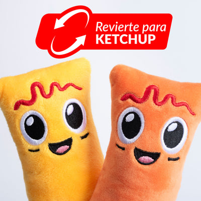 Fotografía de estudio de un acercamiento a los peluches Yuca y Masa mostrando el lado con ketchup bordado, con gráfico "Revierte para Ketchup" sobre la imagen.