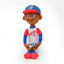 Fotografía de estudio del peluche de Clemente sentado, con uniforme de Puerto Rico #21, gorra azul con visera roja y guante de béisbol en la mano.